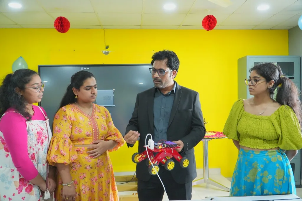 Trainer demonstrating a six-wheeled robot kit to students